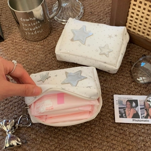 Detail of white star cosmetic bag featuring silver charms on a plush carpet background