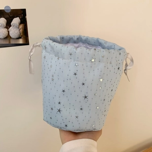 Detail of light blue drawstring bag with silver stars and satin ribbon closure