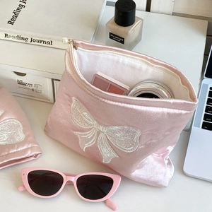 Détail de la trousse de maquillage en satin rose avec broderie et zip en perle