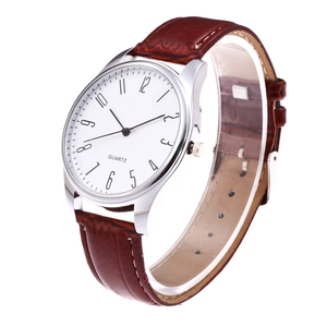 Detail of quartz watch dial with white face and brown alligator texture leather strap