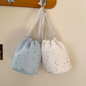 Detail of corduroy drawstring pouches with silver star patterns in blue and white colors