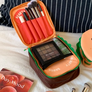 Detail of creative burger makeup bag showing interior brush slots and mesh pocket