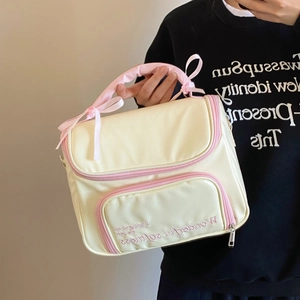 Détail d'une trousse à maquillage blanc crème avec poignée en soie rose et nœuds doux