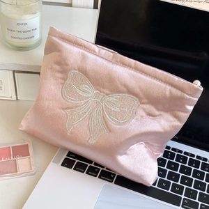 Vue détaillée de la trousse en satin rose avec broderie nœud blanc et zip perle luxe