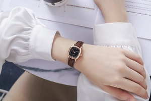 Detailopname van vintage vierkant horloge met zwarte wijzerplaat en bruine leren band