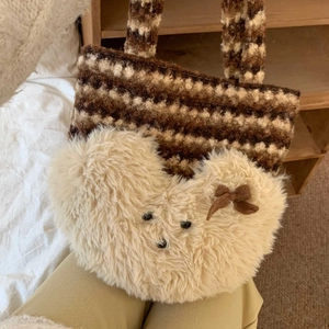 Detail of striped plush tote bag featuring a beige heart pattern and small brown bow