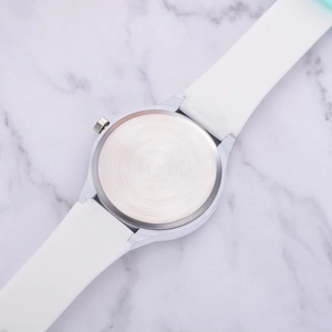 Détail du dos du boîtier en métal argenté brossé et bracelet en silicone blanc
