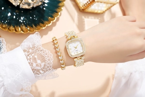 Dettaglio di orologio quadrato dorato con strass e bracciale a cuore abbinato al polso