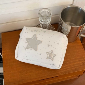 Detail of white star pattern makeup bag on wooden table with silver star patches