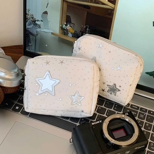 Detail view of two white star-patterned makeup pouches placed on a laptop keyboard