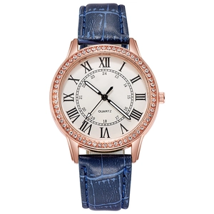 Detail of rose gold watch bezel with rhinestones and navy blue crocodile leather strap