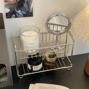 Detail showing a dual-layer stainless steel organizer rack with cosmetics on a dark desk
