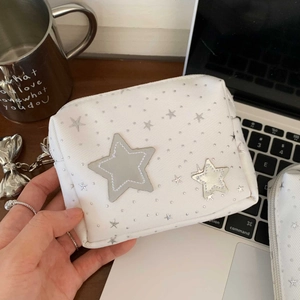 Detail of white corduroy makeup bag with silver stars and metallic bow pendant