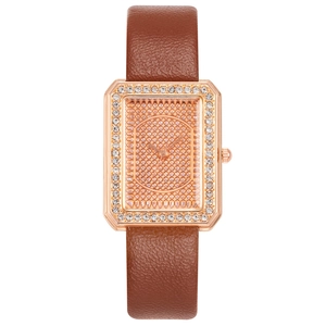 Dettaglio di un orologio rettangolare in oro rosa con strass lucidi e cinturino in pelle marrone