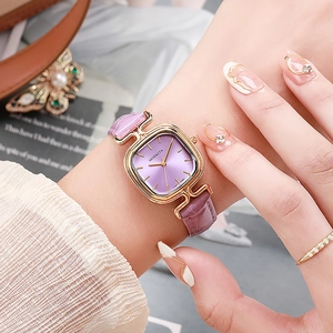 Detail einer quadratischen Golduhr mit lila Zifferblatt und Kroko-Lederarmband