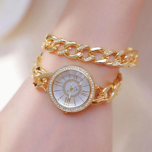 Dettaglio del bracciale a catena dorata e dell'orologio con cristalli sul polso femminile