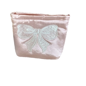 Trousse de maquillage rose nacrée avec broderie nœud blanc et finition satinée