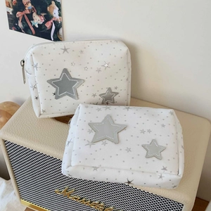 Detail of white star embroidered canvas makeup bag set on a vintage speaker