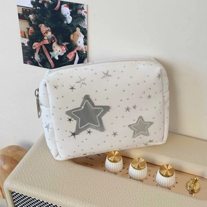 Detail of white star-patterned makeup bag with grey embroidery and silver zipper close-up