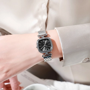 Détail du bracelet en maille argentée et du cadran carré noir sur un poignet féminin
