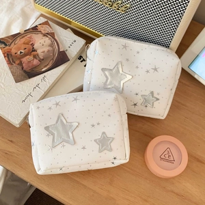 Detail of white star-patterned makeup bags on a desk with elegant lifestyle accessories