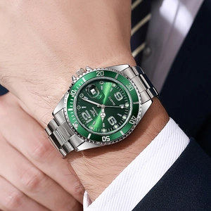 Quartz steel watch with green sunray dial and rotating bezel worn with navy suit