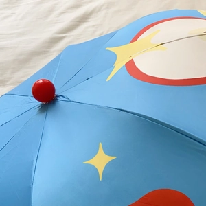 Detail of blue umbrella fabric showing star patterns and a glossy red spherical finial
