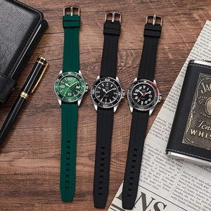 Mens diver style quartz watches with silicone straps and date window on a wooden desk