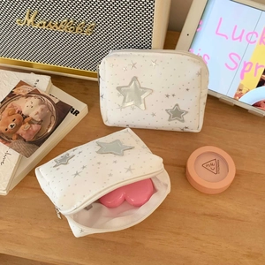 Detail of two-piece white star makeup bags in small and large sizes on a wooden desk