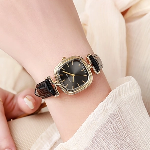 Nahaufnahme einer Vintage-Damen-Goldarmbanduhr mit schwarzem Lederarmband am Handgelenk