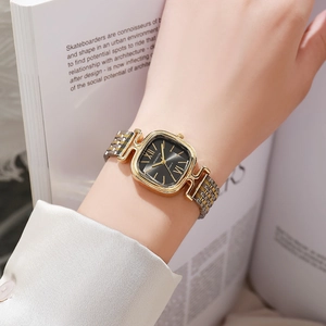 Montre à quartz carrée dorée avec bracelet bicolore et décor de livre élégant au poignet