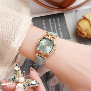 Detail einer eleganten quadratischen Golduhr mit grünem Lederarmband und Zifferblatt