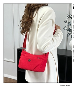 Detail of red nylon crossbody bag with adjustable strap and front zipper pocket