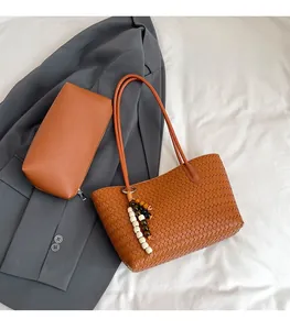 Detailed view of brown woven tote bag with matching pouch and beaded tassel charm