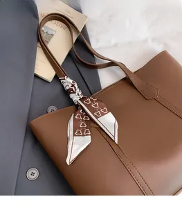 Detail of dark brown leather tote bag with decorative printed scarf and contrast stitching