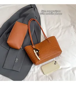 Brown woven tote bag with beads and matching pouch, phone for scale on white cloth