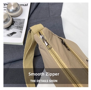 Detail of durable dual alloy zippers and thick nylon strap on a khaki crossbody bag