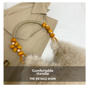 Detail of soft beige faux fur dumpling bag with amber beaded handle and woven rope grip
