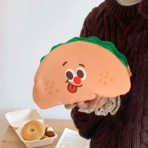 Detail of cute taco-shaped organizer bag with cartoon face held in hand by a model