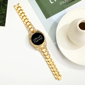 Détail d'une montre LED dorée avec bracelet en strass sur une surface blanche épurée