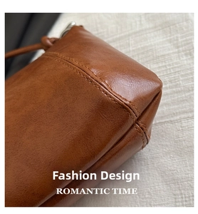 Close-up of precise stitching and premium leather texture on the base of a brown crossbody bag