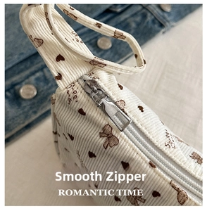 Detailed close-up of a smooth silver zipper on a white corduroy printed crescent bag