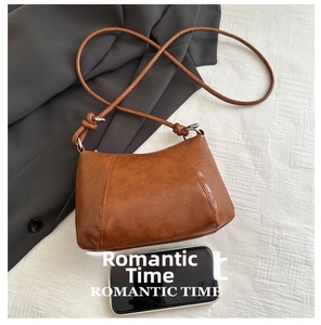 Detailed view of a brown vintage crossbody bag next to a smartphone for size reference