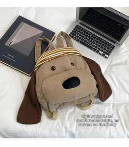 Detail of dog-shaped corduroy backpack with ears and straps on white bed background