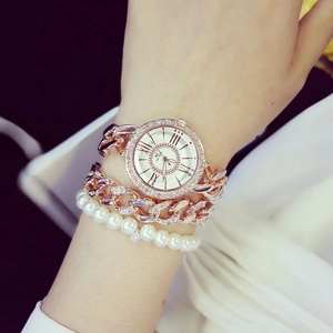 Dettaglio dell'orologio a catena oro rosa e bracciale di perle sul polso con cristalli