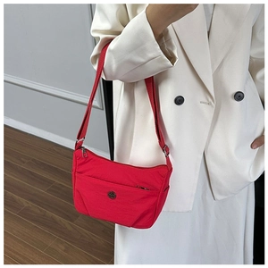 Detail of red nylon crossbody bag with adjustable strap and front zipper pocket