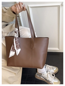 Close-up of dark brown PU leather tote bag with decorative silk scarf and twin handles
