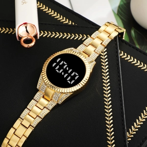 Détail d'une montre LED dorée avec bracelet en strass posée sur un coffret de luxe noir