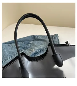 Detailed close-up of the smooth black leather handle with minimalist metallic connectors