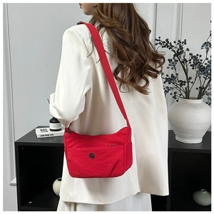 Detail showing the red nylon crossbody bag with logo and wide fabric strap on a model